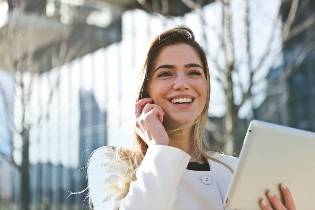 pexels photo 789822 789822 Confident businesswoman using her tablet and phone, smiling outdoors in sunlight.